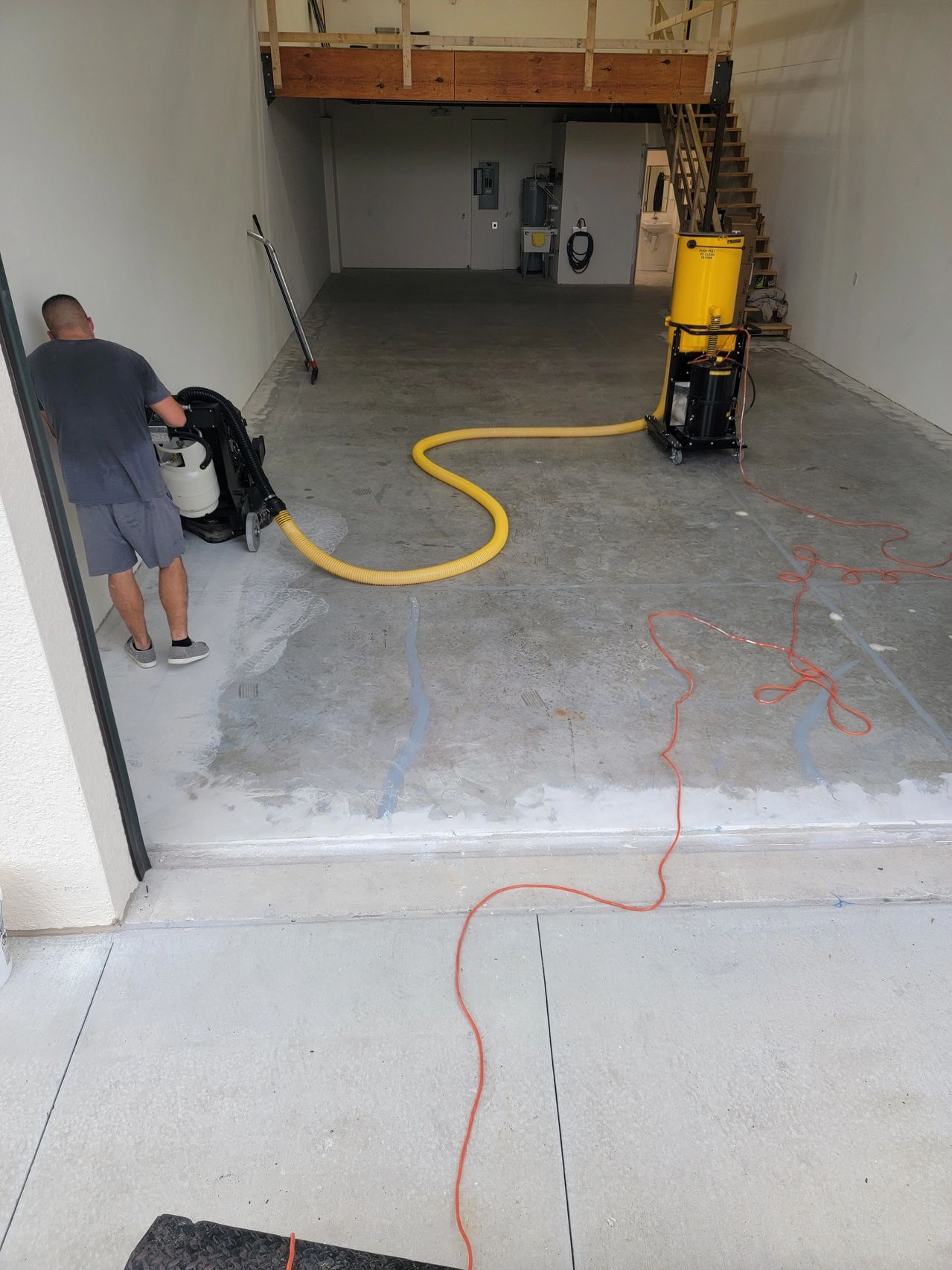 Worker polishing concrete floor in empty garage