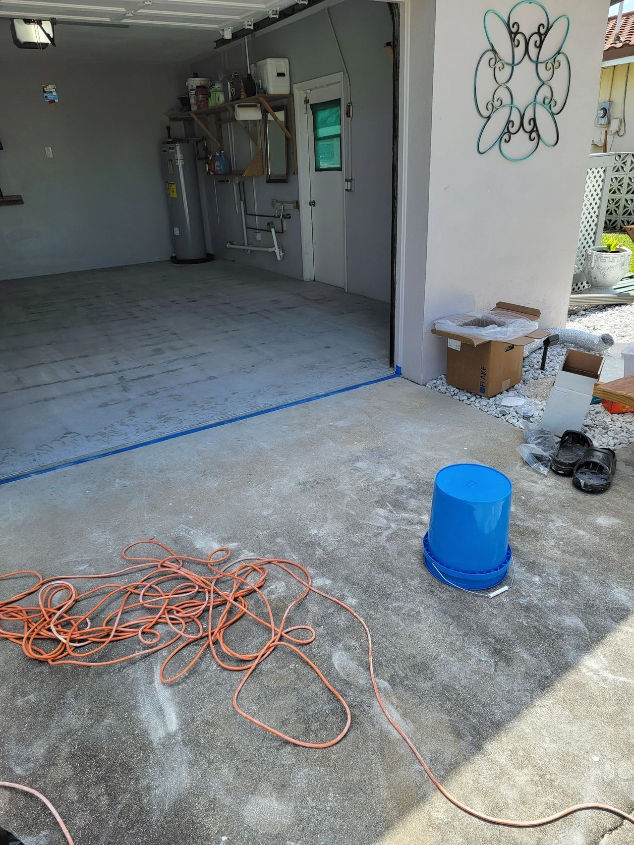 Open garage with coiled orange cord, blue bucket