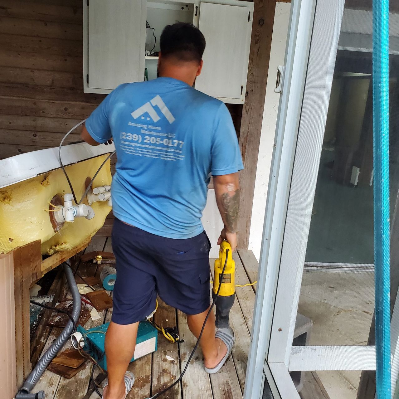 Man in blue shirt using yellow power tool