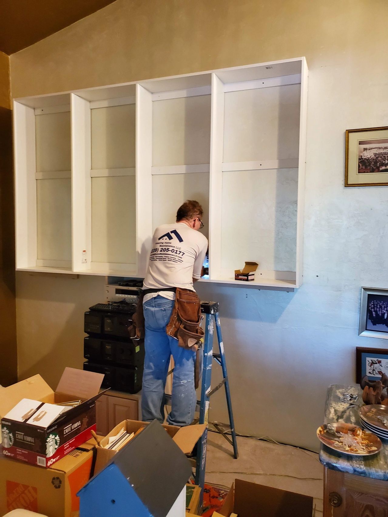 Worker installing white wall-mounted kitchen cabinets