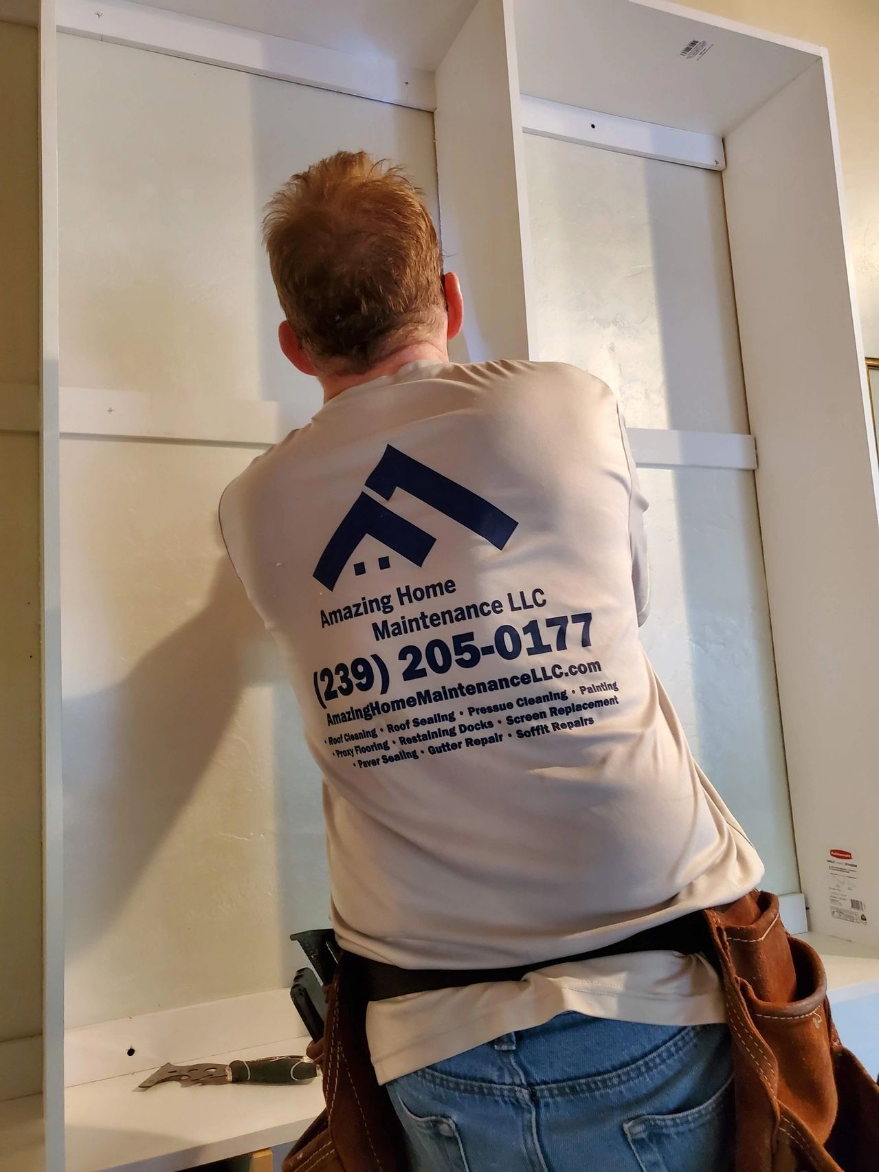 Home maintenance worker installing white cabinet