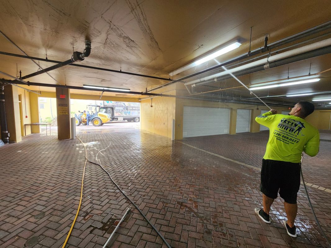 AHCM technician pressure washing the ceiling of a covered parking garage