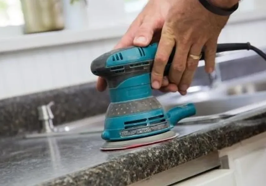 Handheld orbital sander on kitchen countertop