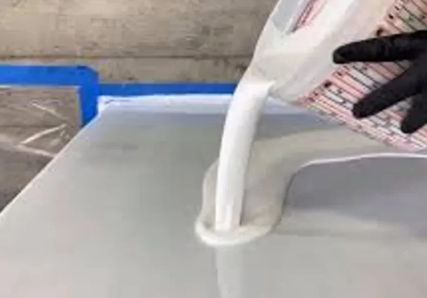 Black-gloved hand pouring white liquid onto surface