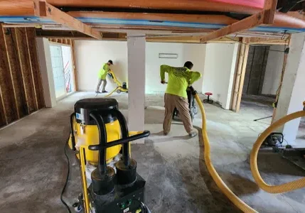 Workers grinding concrete floor with vacuum system