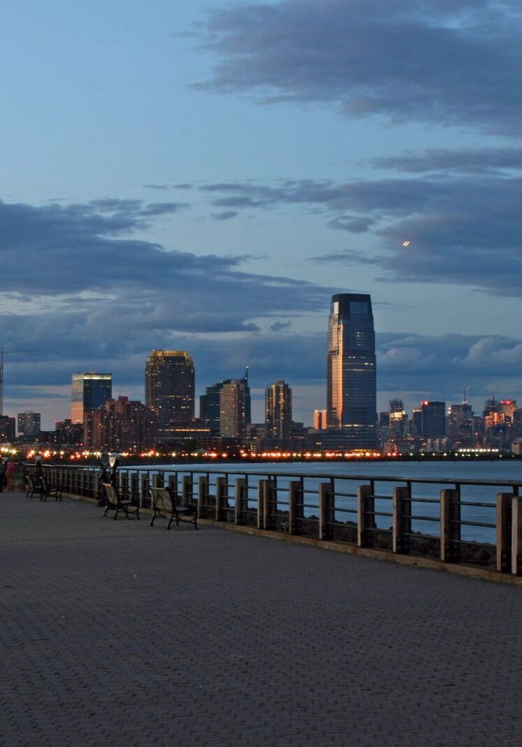 Waterfront promenade with city skyline at dusk