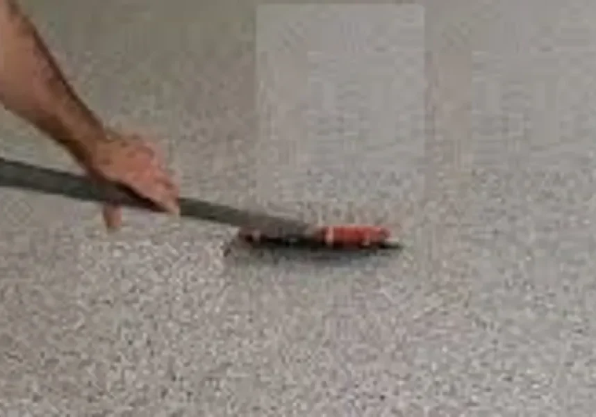 Worker applying epoxy floor coating with squeegee
