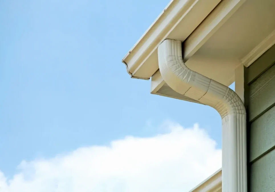White house downspout against clear blue sky