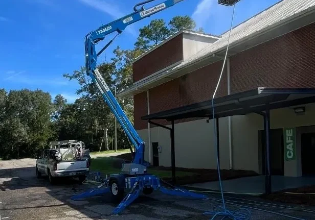 Blue boom lift beside brick building roof