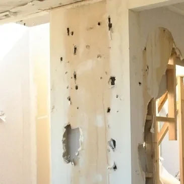 Damaged interior wall with bullet holes