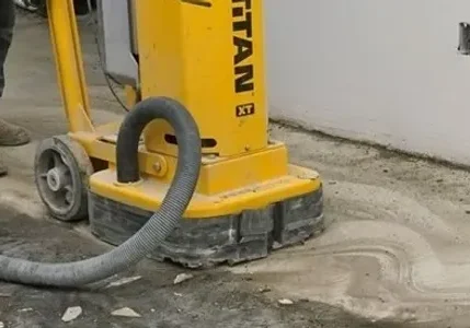 Yellow concrete floor grinder with vacuum hose