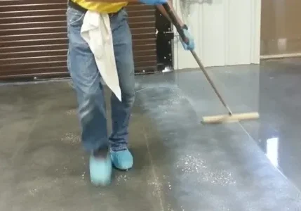 Person mopping concrete floor wearing blue shoes