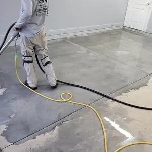 Worker polishing concrete floor with grinder