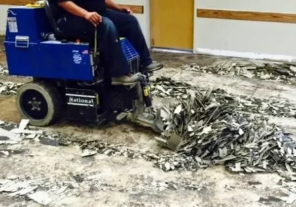 Worker operating floor scraper removing old flooring